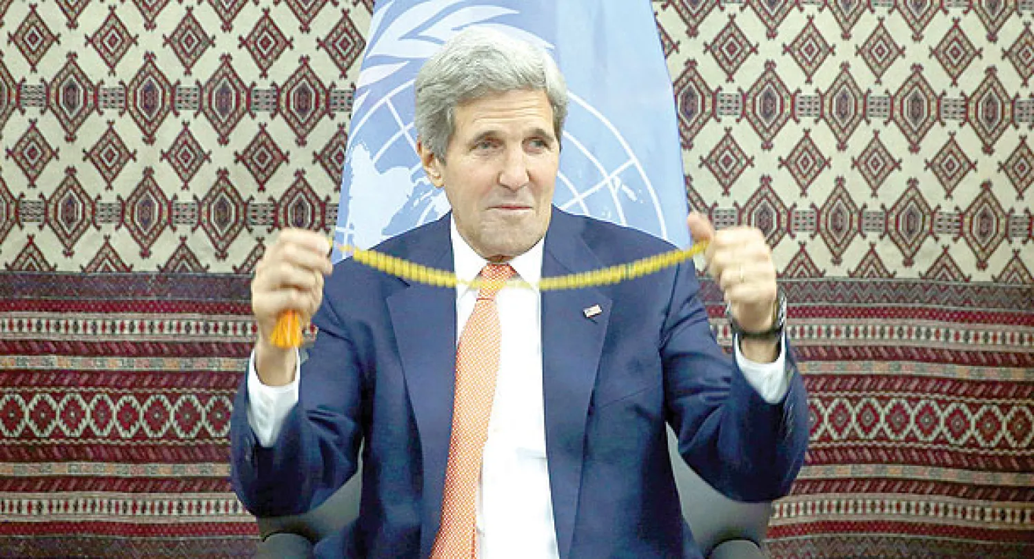 جون كيري يستعرض سبحة أهديت إليه بعد لقائه مرشحي انتخابات الرئاسة الأفغانية في العاصمة كابل أمس (إ.ب.أ)