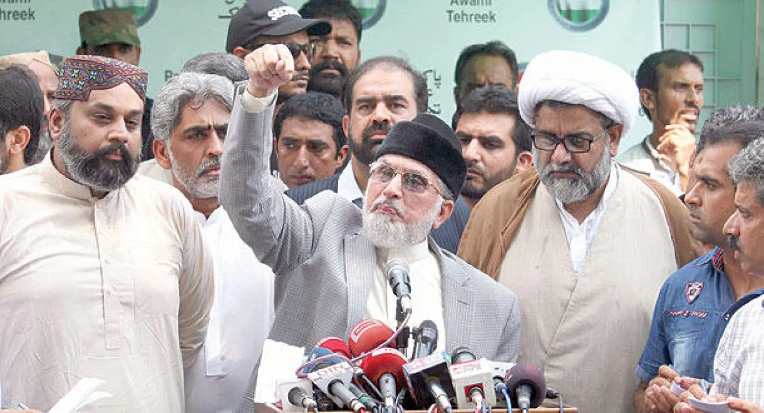 طاهر القادري مع عدد من مناصريه خلال ندوة صحافية أقامها في لاهور أمس (أ.ب)
