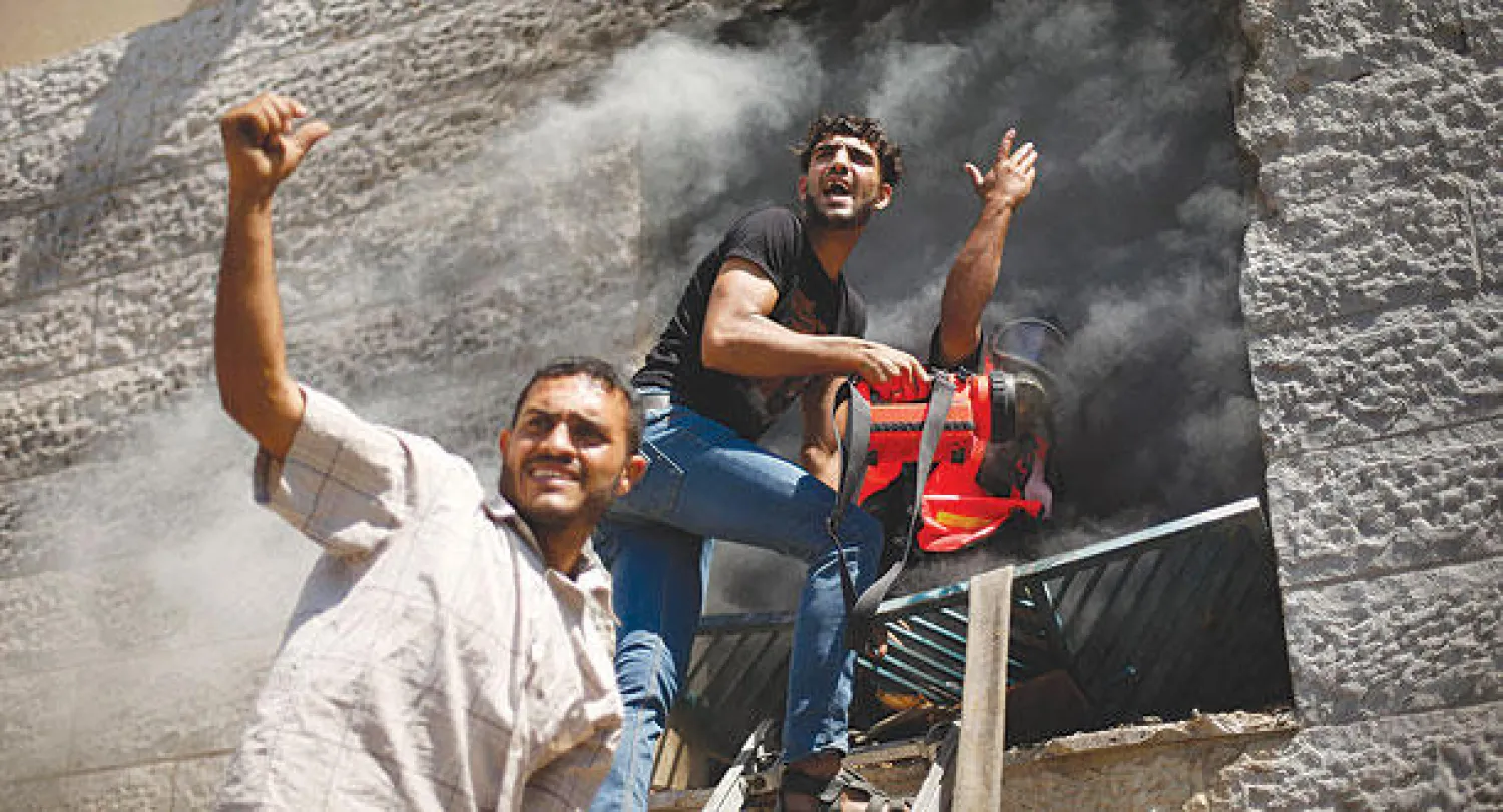 فلسطينيان يحاولان إخماد حريق اندلع في شقة جراء غارة إسرائيلية على بيت لاهيا شمال قطاع غزة أمس (رويترز)