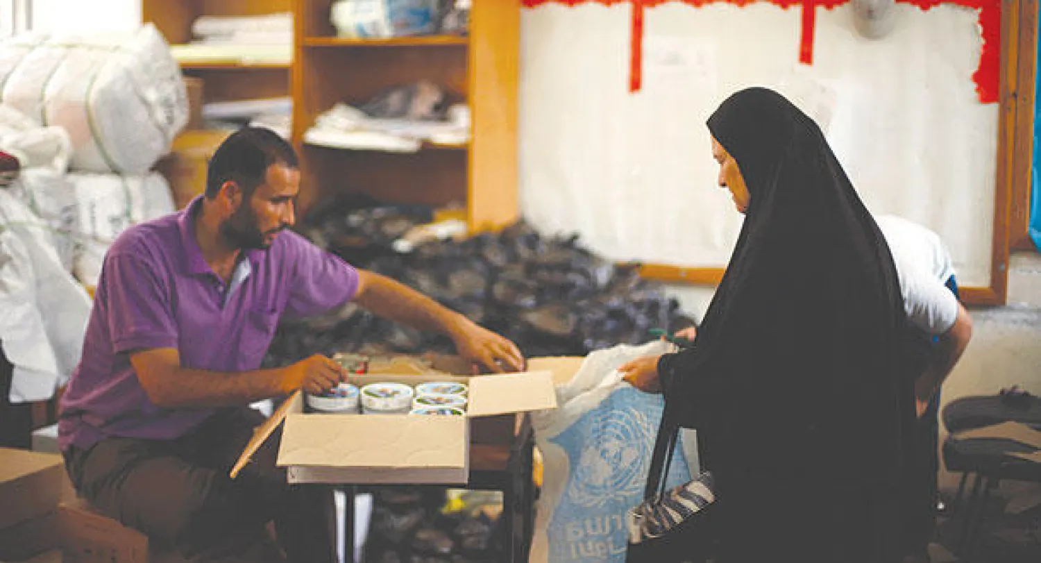 فلسطينية تتسلم مساعدات غذائية وزعتها الأمم المتحدة على النازحين من جباليا في قطاع غزة أمس (رويترز)
