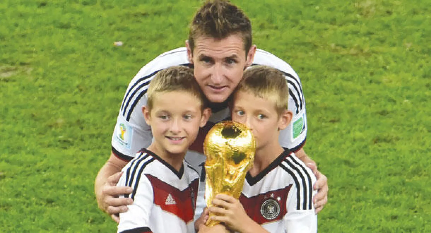 الهداف الألماني يتوسط أبنيه بعد تحقيق كأس العالم (أ.ف.ب)