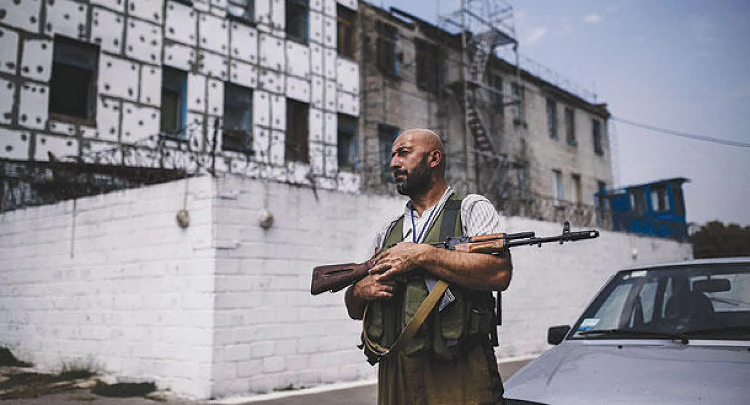 أحد عناصر المتمردين في شرق أوكرانيا في نوبة حراسة لسجن هرب منه المئات من السجناء بالقوة  في دونيتسك، معقل المتمردين بعد أن تعرض المبنى لقصف مدفعي (أ.ف.ب)