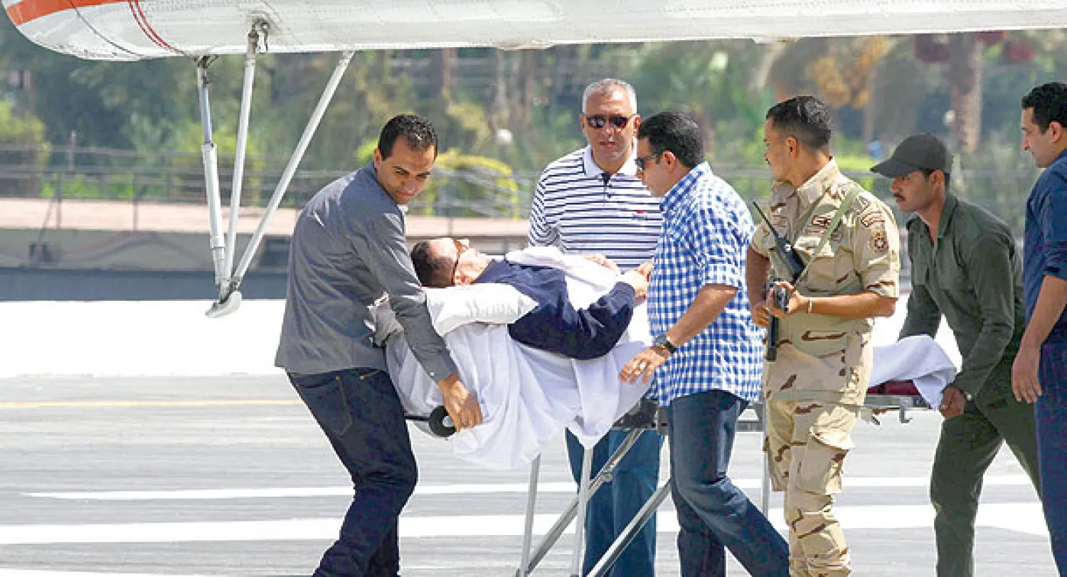 الرئيس المصري السابق حسني مبارك أثناء نقله من الهليوكوبتر إلى قاعة محكمة القاهرة أمس (إ ب أ)