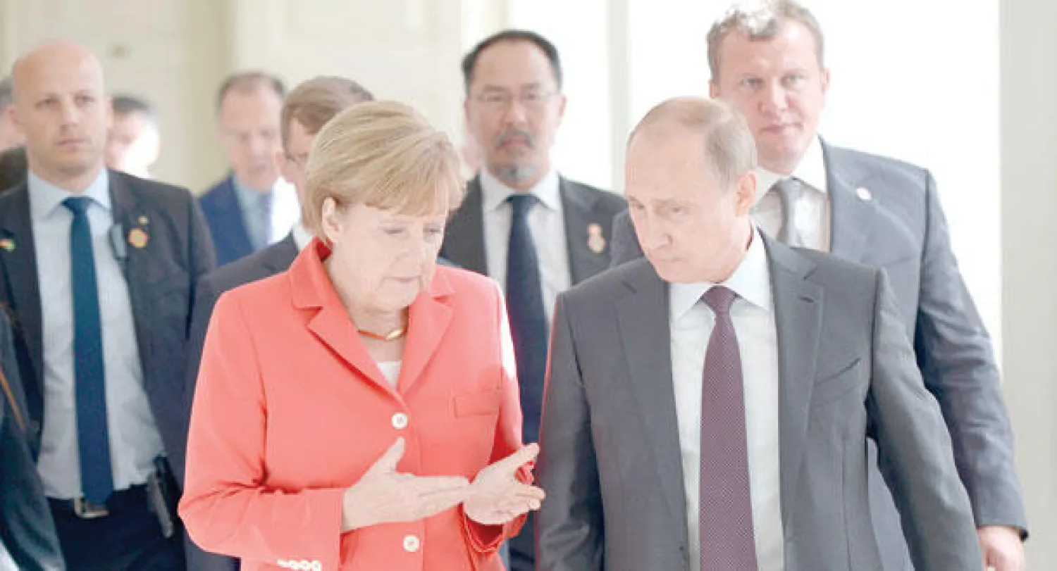 الرئيس الروسي فلاديمير بوتين والمستشارة الألمانية أنجيلا ميركل أثناء محادثة جانبية قبل بدء المباراة النهائية في بطولة كأس العالم الشهر الماضي (أ. ب)