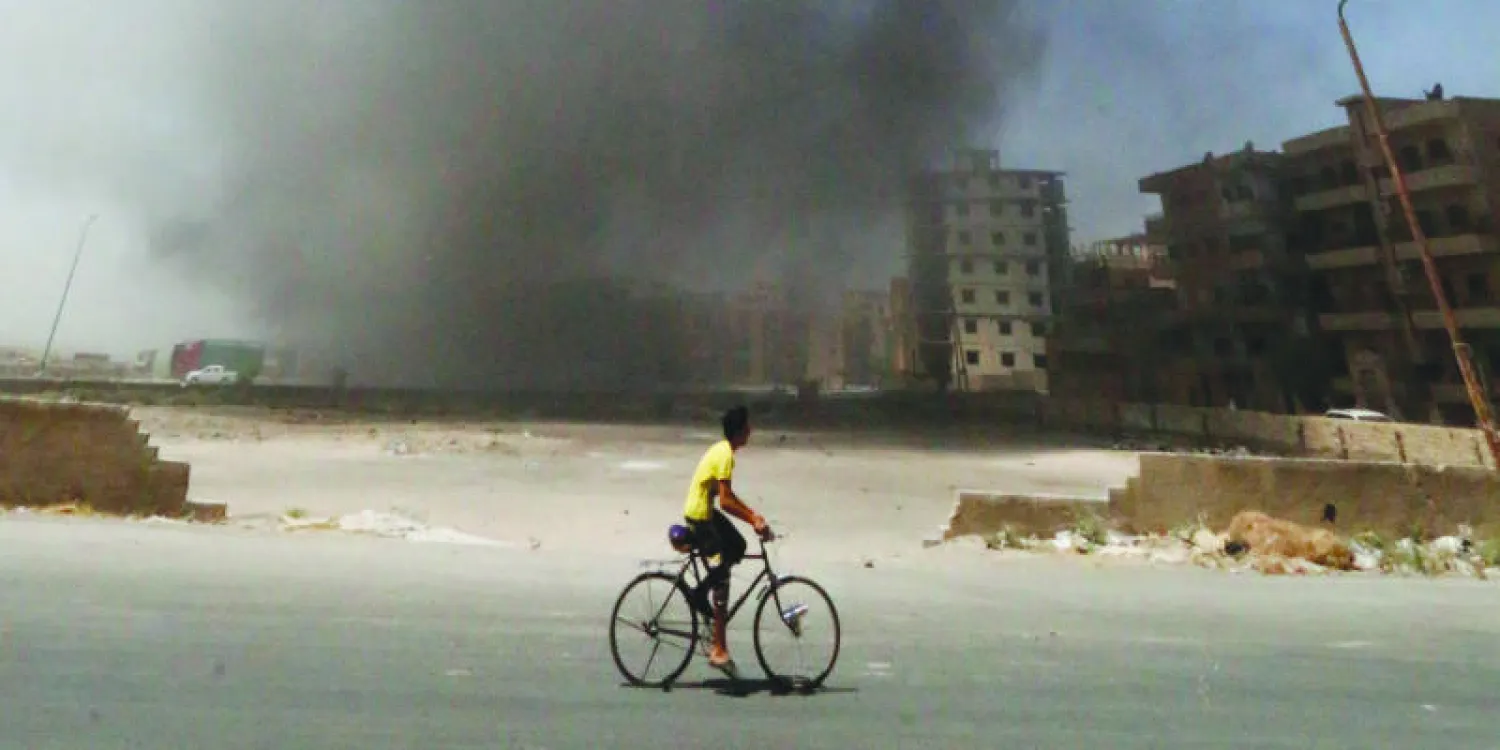 سوري يعاين عمودا من الدخان انطلق في سماء الرقة إثر غارة جوية نظامية على معاقل «داعش» في المدينة أمس (رويترز)