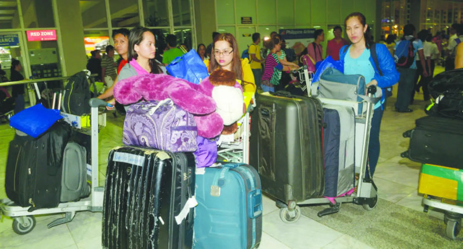 فيلبينيون لدى وصولهم إلى مطار نينوي أكينو في مانيلا أمس بعد مغادرتهم ليبيا جراء تصارع الميليشيات فيها (أ.ف.ب)