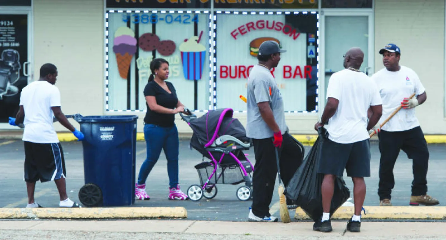 متطوعون يزيلون آثار العنف والتخريب بعد ليلة دامية في شوارع فيرغسون بولاية ميسوري أمس (رويترز)