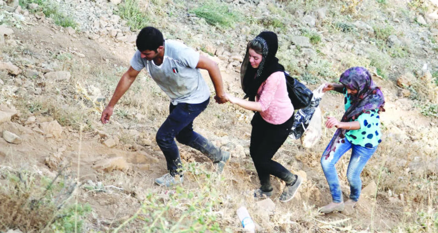 نازحون إيزيديون يتسلقون جبلا قرب شرناخ على الحدود التركية - العراقية أول من أمس (إ.ب.أ)