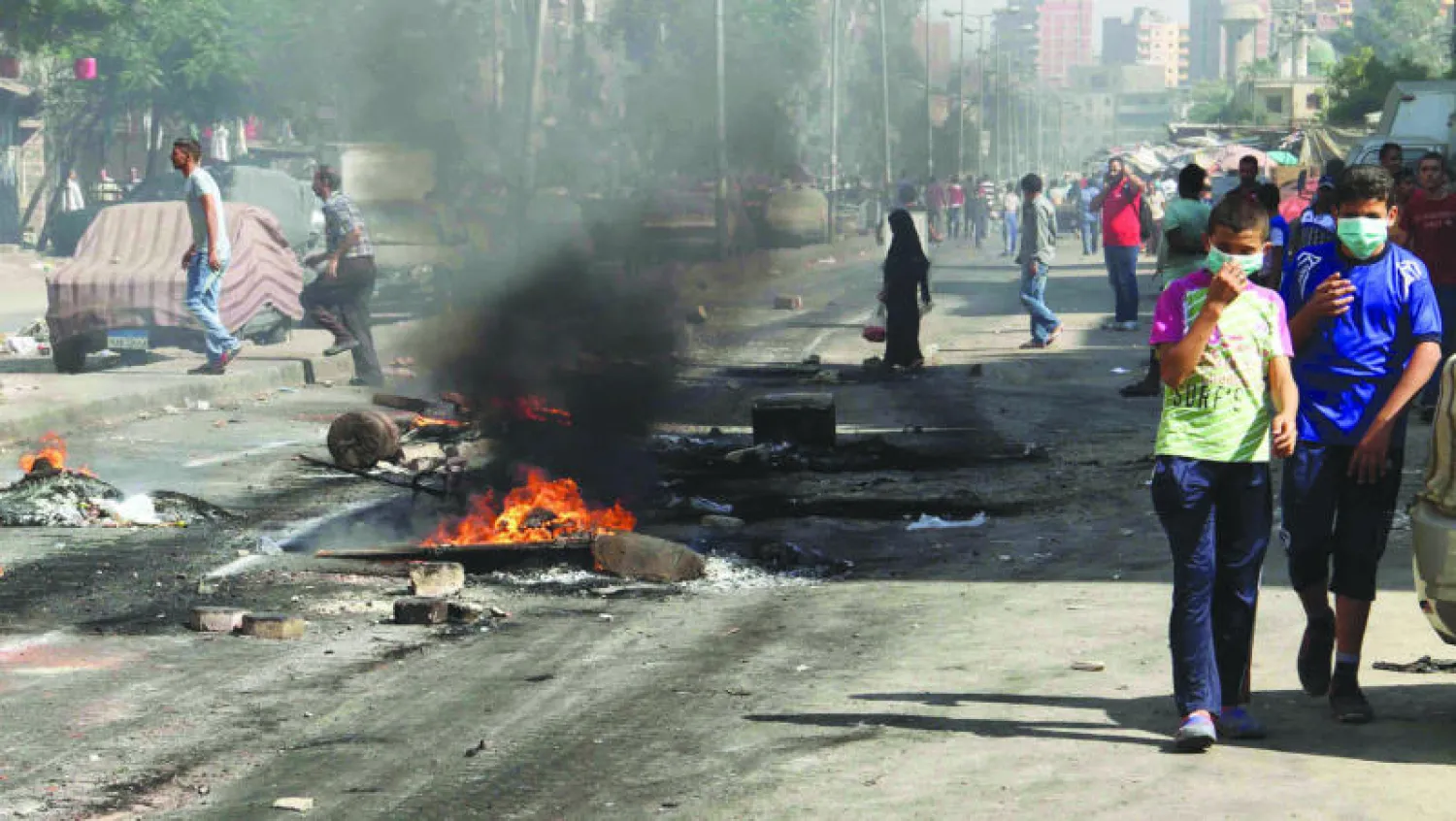 صبيان يسيران وسط ما خلفته المواجهة بين قوات الأمن المصرية ومؤيدي الرئيس السابق محمد مرسي في حي المطرية أمس (إ.ب)