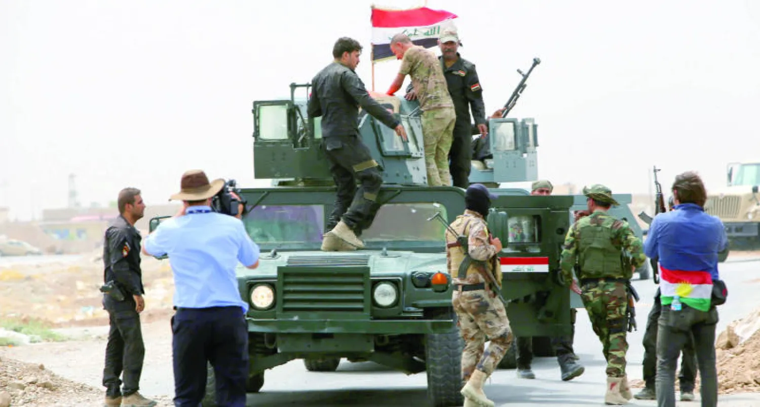 عناصر من قوات مكافحة الإرهاب في الجيش العراقي يلوحون بالعلم العراقي عند نقطة تفتيش في قرية البدرية غربي الموصل أمس (أ.ف.ب)