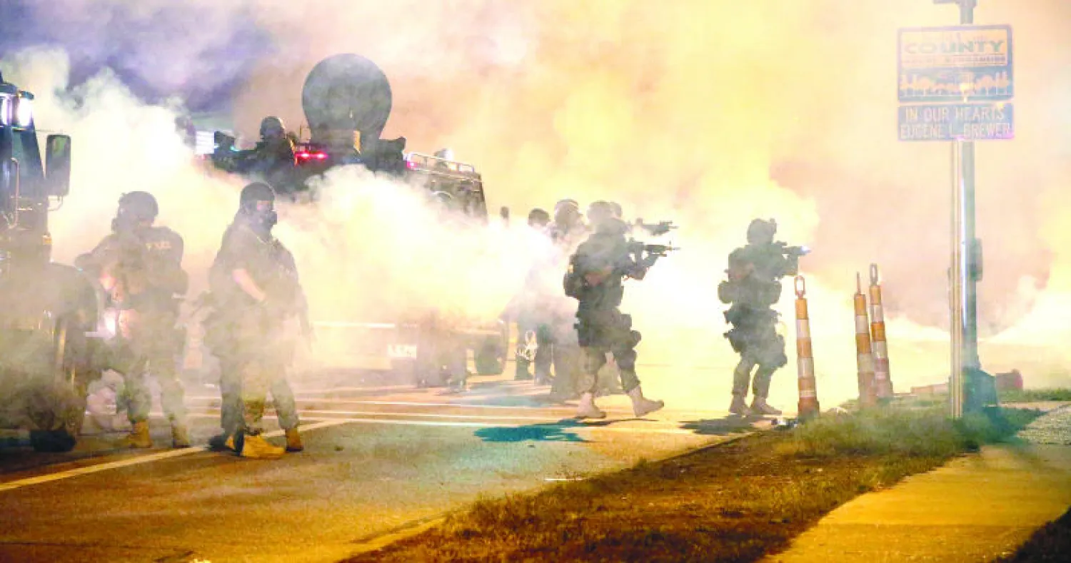 رجال شرطة يواجهون المتظاهرين مساء أول من أمس في فيرغسون..والصورة مأخوذة بعدسة مصورة وكالة «غيتي» سكوت أولسون الذي اعتقل أمس لساعات عدة (أ.ف.ب)