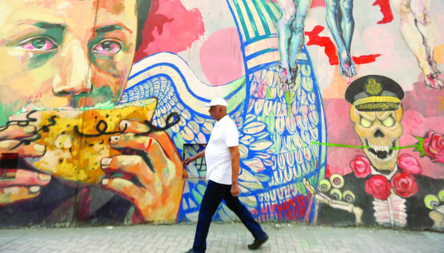 مصري يمر بالقرب من رسم غرافيتي قرب ميدان التحرير أمس (رويترز)