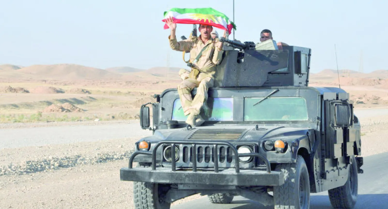 عنصر في قوات البيشمركة يرفع علم كردستان وهو جالس على عربة عسكرية خلال مواجهات في جلولاء أول من أمس (رويترز)