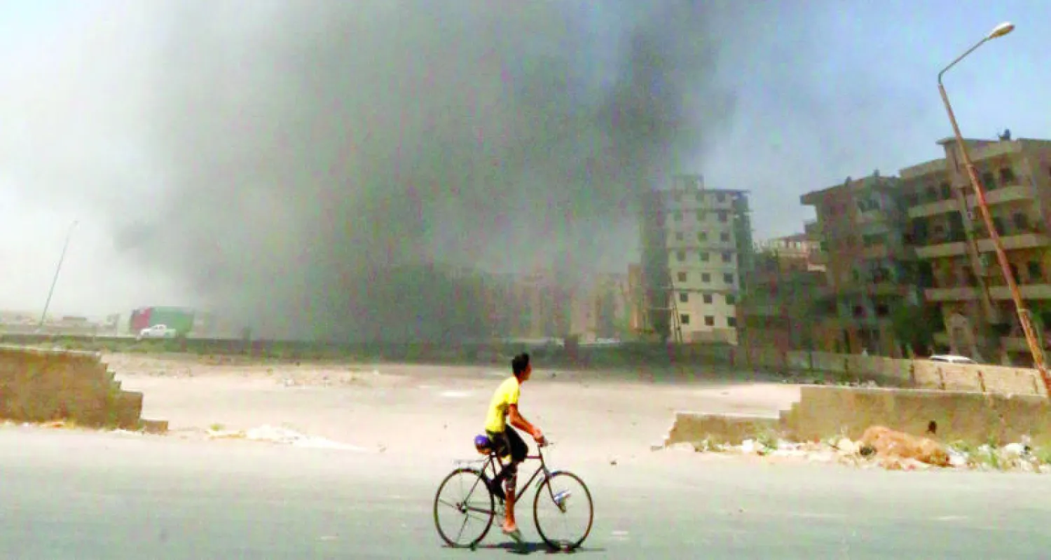 شاب يمر على دراجته بمنى في محافظة الرقة قصفته قوات النظام السوري وقد تصاعدت منه أعمدة الدخان (رويترز)