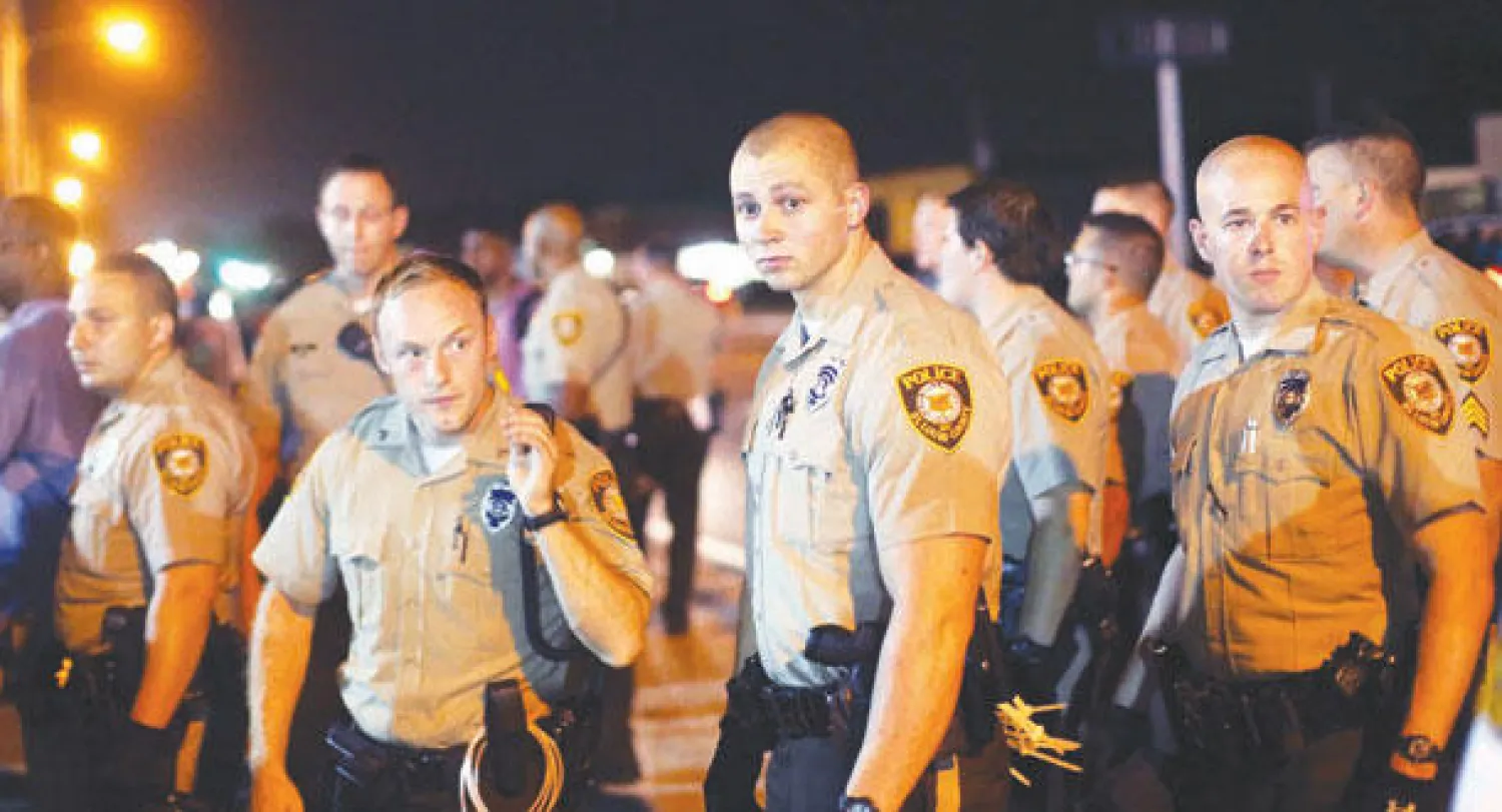 رجال شرطة يراقبون متظاهرين في فيرغسون ليل أول من أمس (أ.ف.ب)