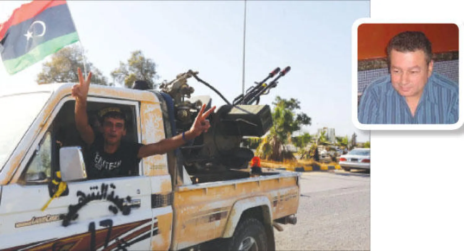 أحد المسلحين يرفع شارة النصر بعد السيطرة على مطار طرابلس الدولي أمس (أ.ف.ب) وفي الاطار مستشار الجيش الوطني الليبي محمد بويصير