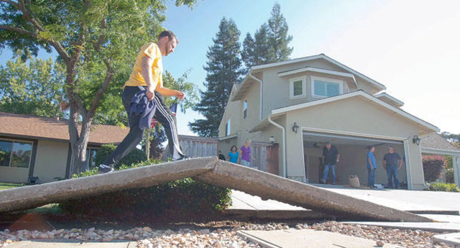أميركي يسير على رصيف أمام منزله تأثر بزلزال كاليفورنيا (إ.ب.أ)