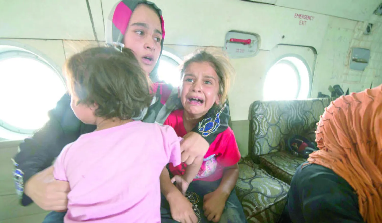 امرأة مع طفليها على متن مروحية تابعة للجيش العراقي أجلتهم أمس من بلدة آمرلي التركمانية الشيعية المحاصرة الواقعة إلى الشمال من بغداد (رويترز)