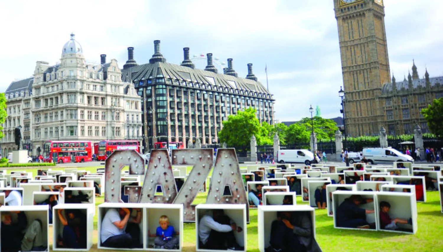 متطوعون بريطانيون يجلسون بصناديق كرتونية في ساحة البرلمان في لندن لتمثيل الأوضاع وتوضيح الظروف التي واجهها سكان غزة أثناء الحصار الإسرائيلي أمام المسؤولين البريطانيين (غيتي)