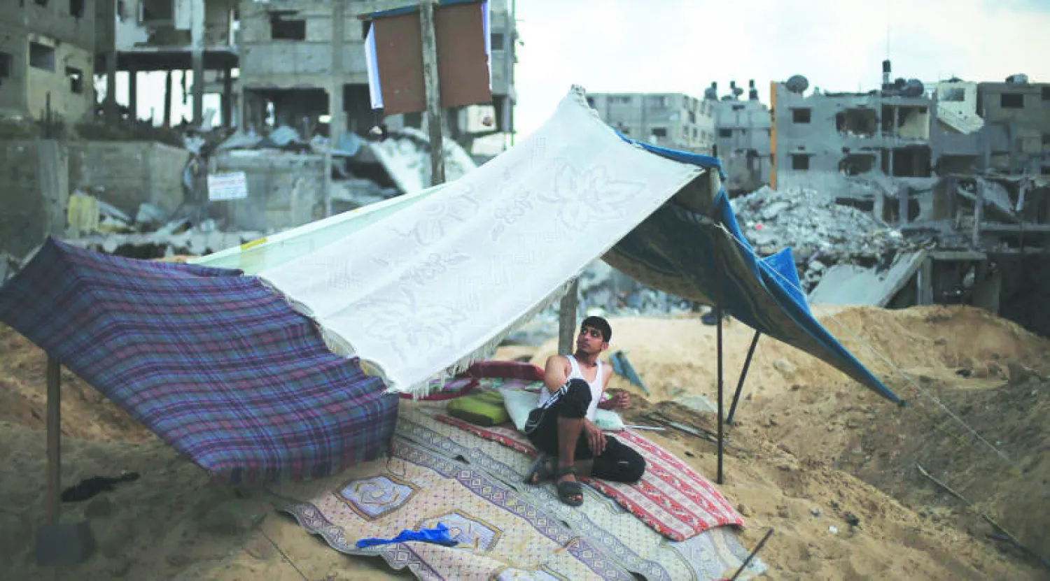 فلسطيني نصب خيمة قرب منزله الذي دمر كليا في حي الشجاعية بغزة (رويترز)