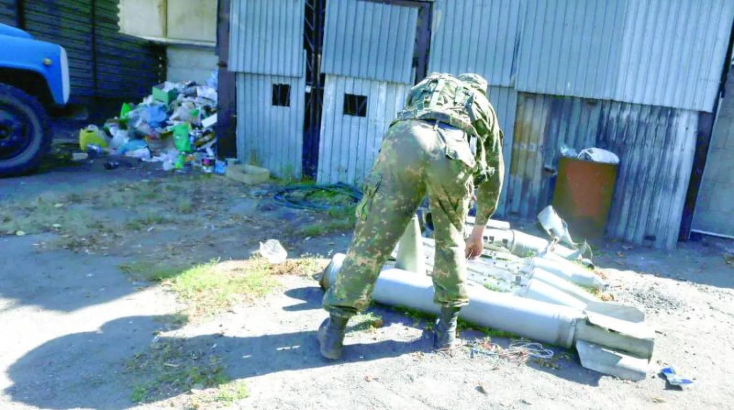 عنصر من ميليشات الدفاع الوطني الموالية لروسيا يتفقد بقايا صواريخ وقذائف أوكرانية في بلدة يسيطر عليها المتمردون في شرق أوكرانيا أمس (ا.ف.ب)