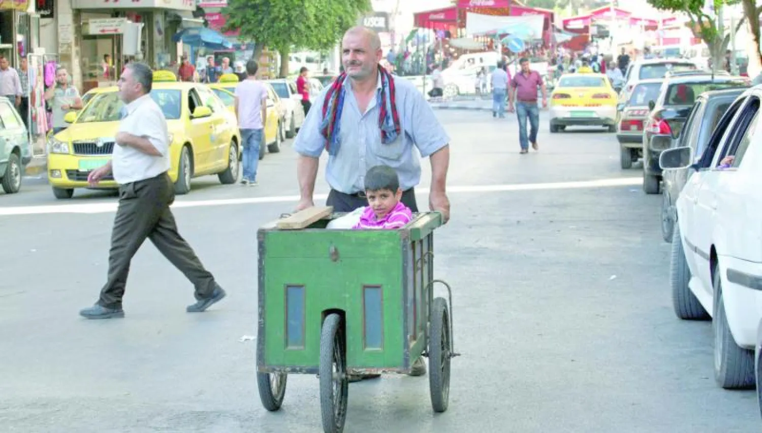 فلسطيني يدفع نجله بعربة في سوق بمدينة نابلس في الضفة الغربية أمس (أ.ب)