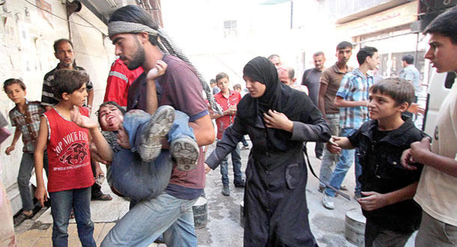 عائلة سورية تحمل طفلها الجريح إلى مستشفى دوما إثر قصف القوات النظامية على المدينة أمس (رويترز)