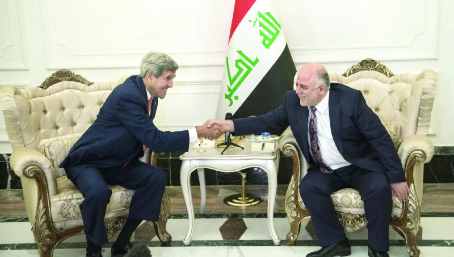 رئيس الوزراء العراقي حيدر العبادي يصافح وزير الخارجية الأميركي جون كيري في مستهل لقائهما ببغداد أمس (أ.ب)