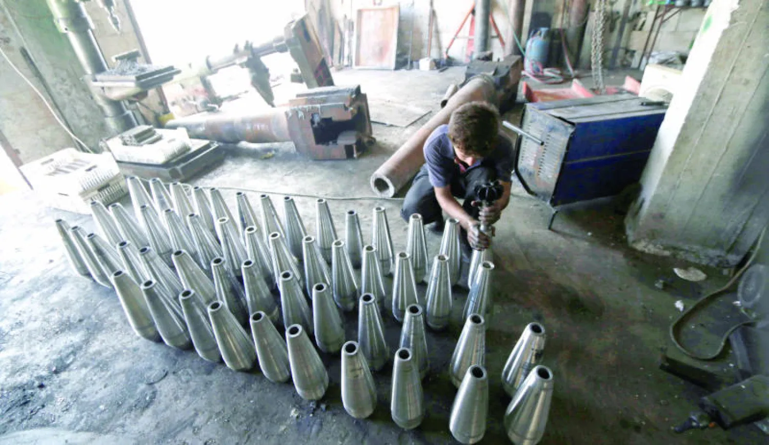 مقاتل سوري أثناء عمله في مصنع للأسلحة بإدلب أمس (رويترز)