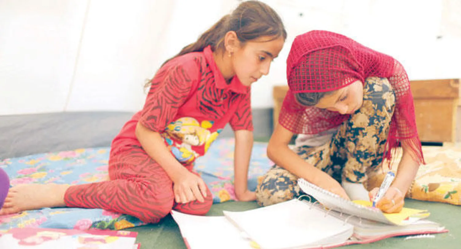 طفلتان عراقيتان  نزحتا مع عائلتهما من الموصل تدرسان في مخيم بحركة للاجئين بالقرب من أربيل (رويترز)