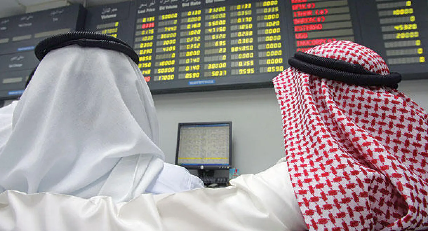 متعاملان بحرينيان يراقبان شاشات عرض المعلومات في سوق أبو المنامة للأوراق المالية (أ.ف.ب)
