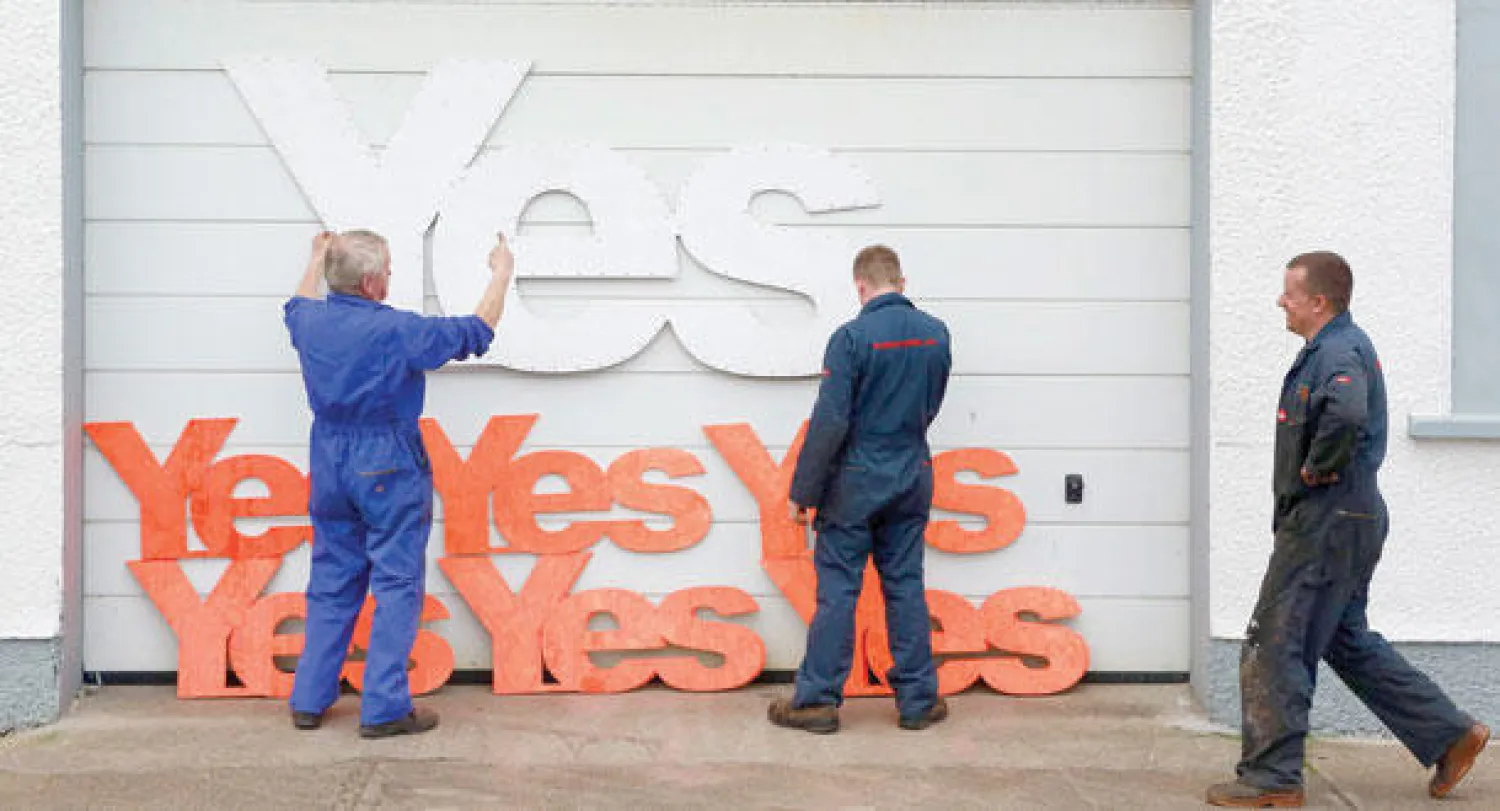 موظفون يضعون شعارات مختلفة الأحجام لحملة «نعم» المؤيدة لانفصال اسكوتلندا عند مدخل محلهم في منطقة ستورنواي التابعة لجزيرة لويس الاسكوتلندية أمس (رويترز)