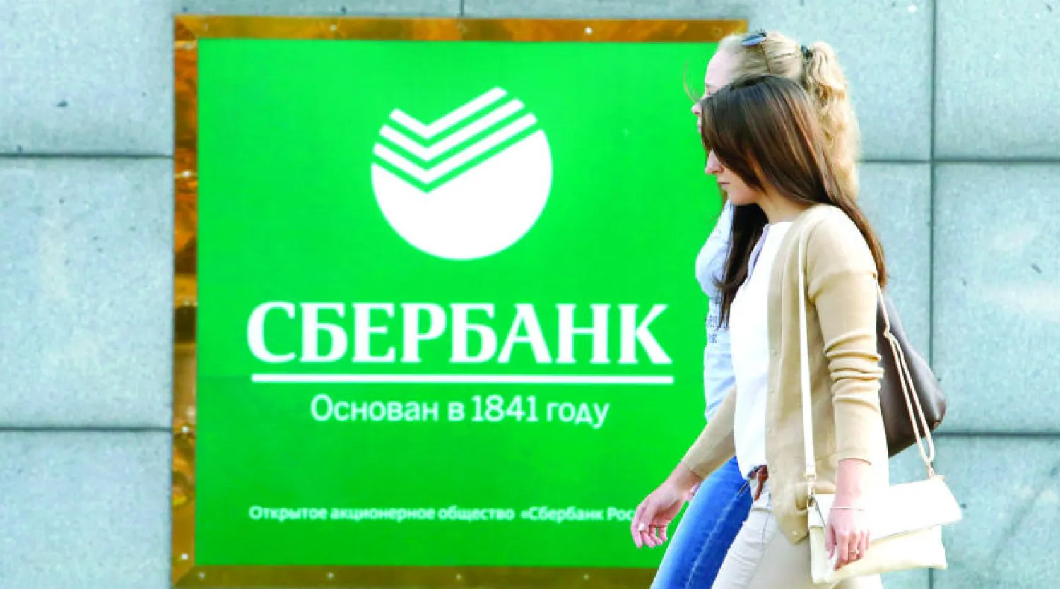 شابتان تمران أمام أحد فروع «سبيربنك» الذي طالته العقوبات الأميركية الجديدة في موسكو أمس (رويترز)