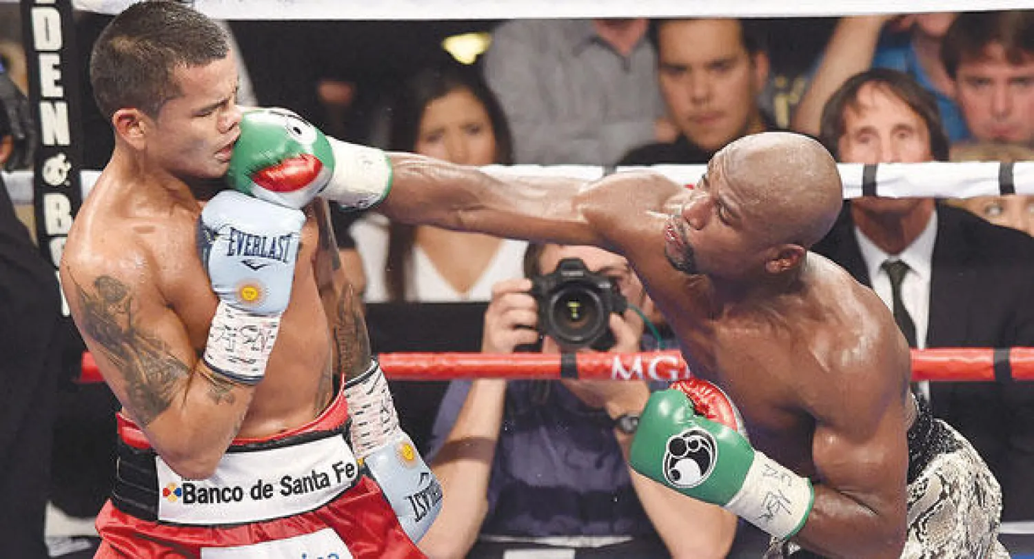 مايويذر(يمين) يوجه لكمة مباشرة إلى ميدانا (أ.ف.ب)