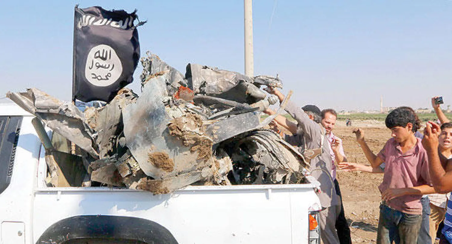 سوريون جمعوا أشلاء الطائرة التابعة للطيران الحربي للنظام السوري والتي أسقطها «داعش» في الرقة أمس (رويترز)