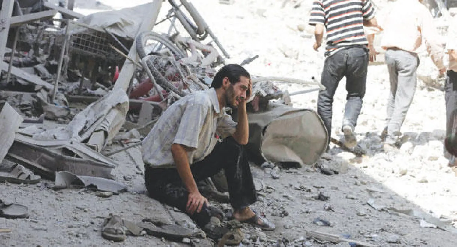 سوري متأثر بالدمار الذي خلفته غارتان لطائرات نظام الأسد على سوق وسط منطقته دوما شرق الغوطة أمس (رويترز)