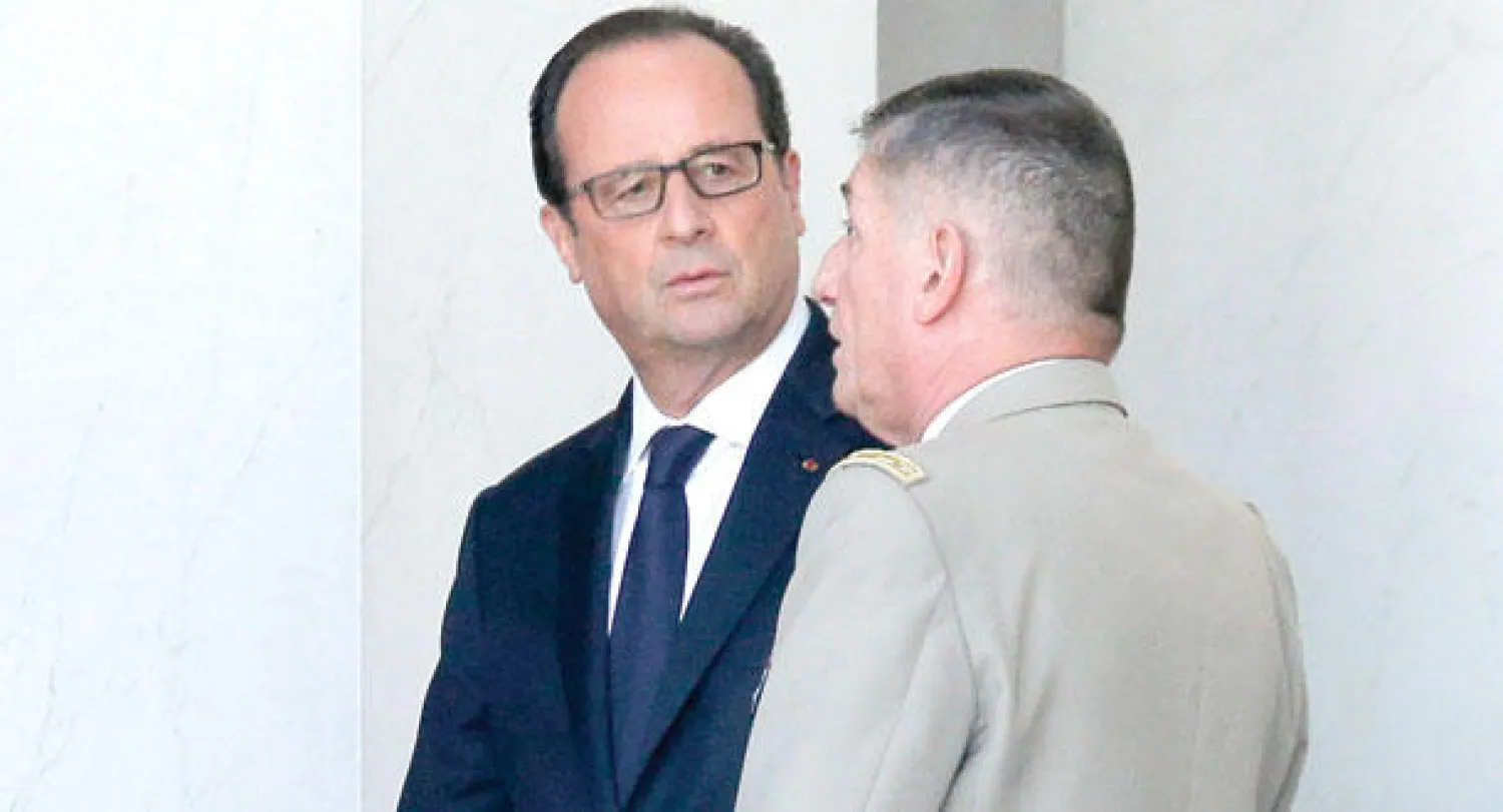 الرئيس الفرنسي فرنسوا هولاند يتحدث مع رئيس هيئة أركان الجيش بعد مؤتمر صحافي عقده في قصر الإليزيه في باريس أمس (أ.ف.ب)