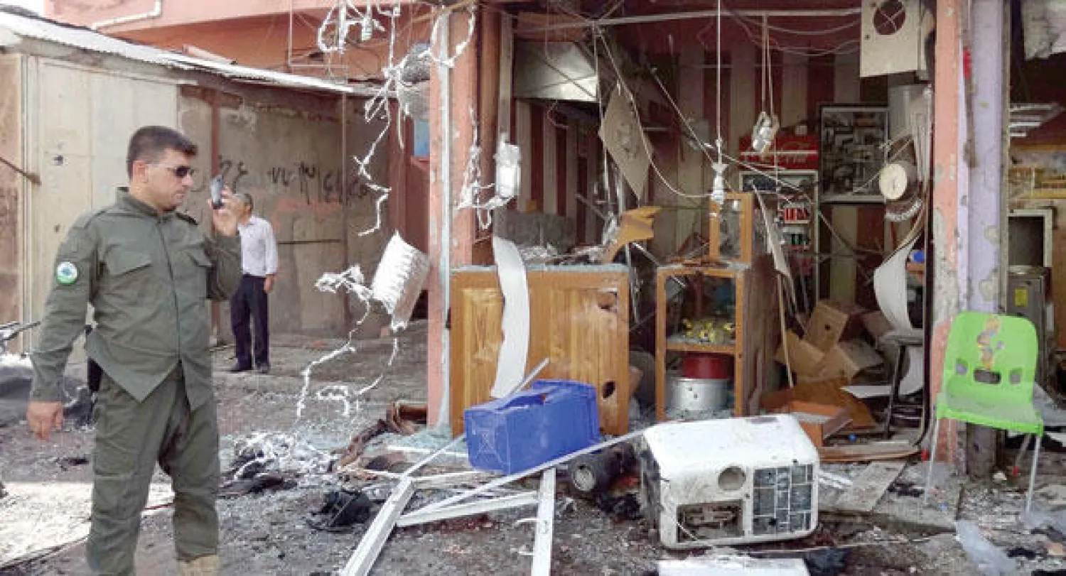 شرطي عراقي يتفقد موقع الهجوم بقنبلة في وسط كركوك (أ.ف.ب)