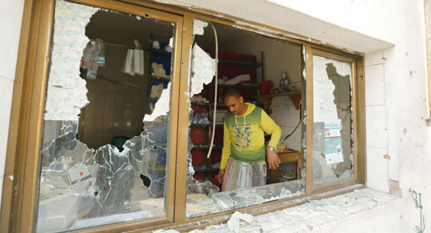 عامل يتفقد الأضرار التي لحقت بمدرسة في منطقة قريبة من موقع الاشتباكات بين القوات الحكومية ومسلحي جماعة الحوثيين أمس (رويترز)