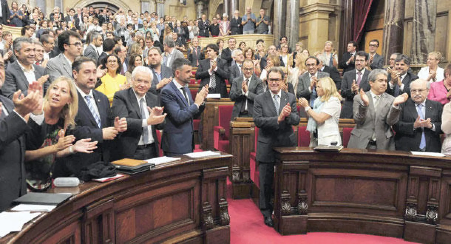 رئيس إقليم كتالونيا آرتور ماس (الرابع من اليمين) ونواب يصفقون بعد موافقة البرلمان الإقليمي، في برشلونة أمس، على قانون لتنظيم الاستفتاء في 9 نوفمبر المقبل (أ.ف.ب)