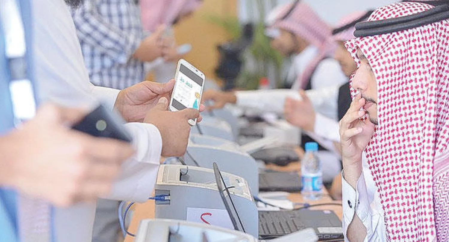 مسؤول يشرح لأحد الشباب منصة برنامج خطط الإلكترونية («الشرق الأوسط»)