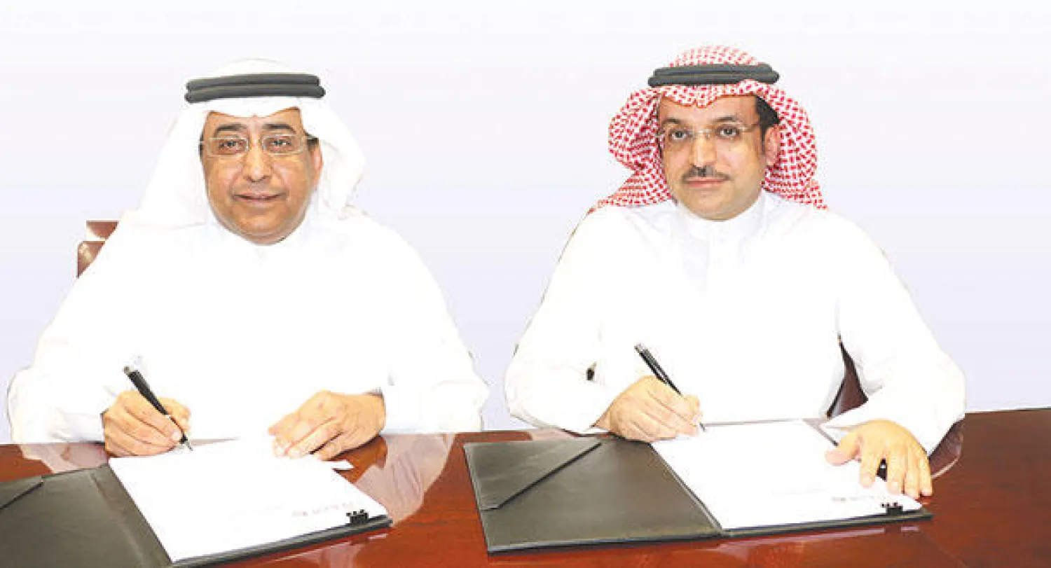 القضيبي والمرشد خلال توقيع الاتفاقية («الشرق الأوسط»)