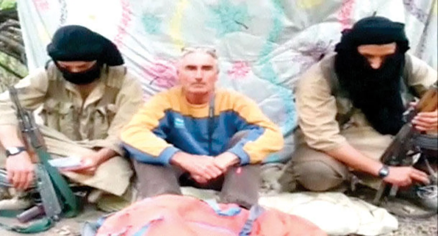 رجل عرف نفسه على أنه هيرفي غوردل يجلس بين مسلحين حيث تم اختطافه في شرق الجزائر (رويترز)