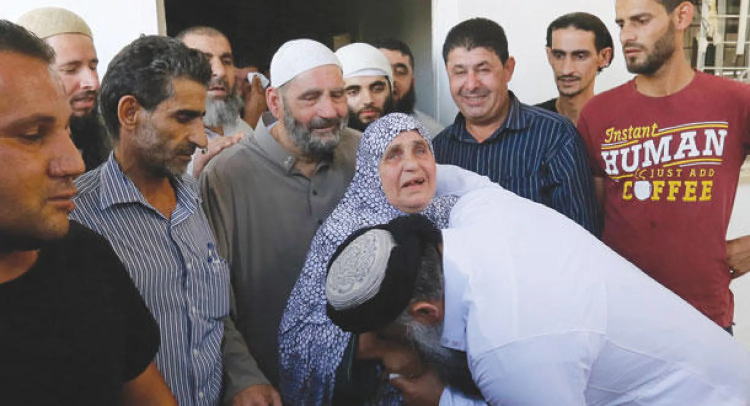 أبو قتادة يقبل يد والدته بعد الإفراج عنه من سجن قرب العاصمة الأردنية عمان أمس (رويترز)