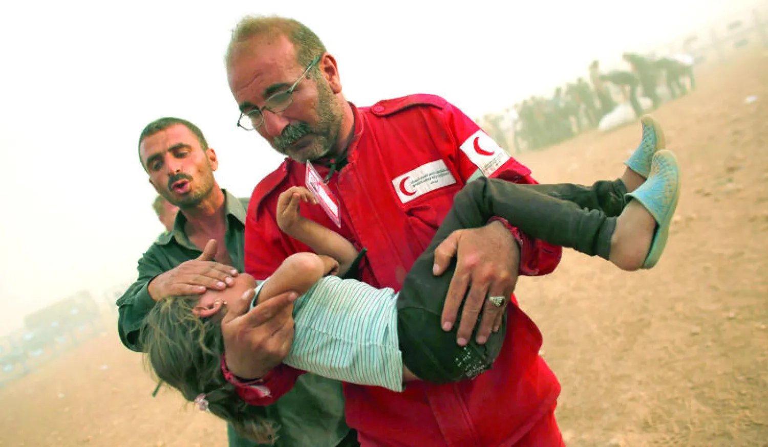 عضو من الهلال الأحمر السوري يحمل طفلة لاجئة لإعطائها الإسعافات الأولية داخل خيمة بعد عبور الحدود مع تركيا في منطقة سانليورفا أمس.. وكان نحو 140 ألفا من أكراد سوريا قد فروا باتجاه تركيا خلال الأسبوع الحالي (رويترز)