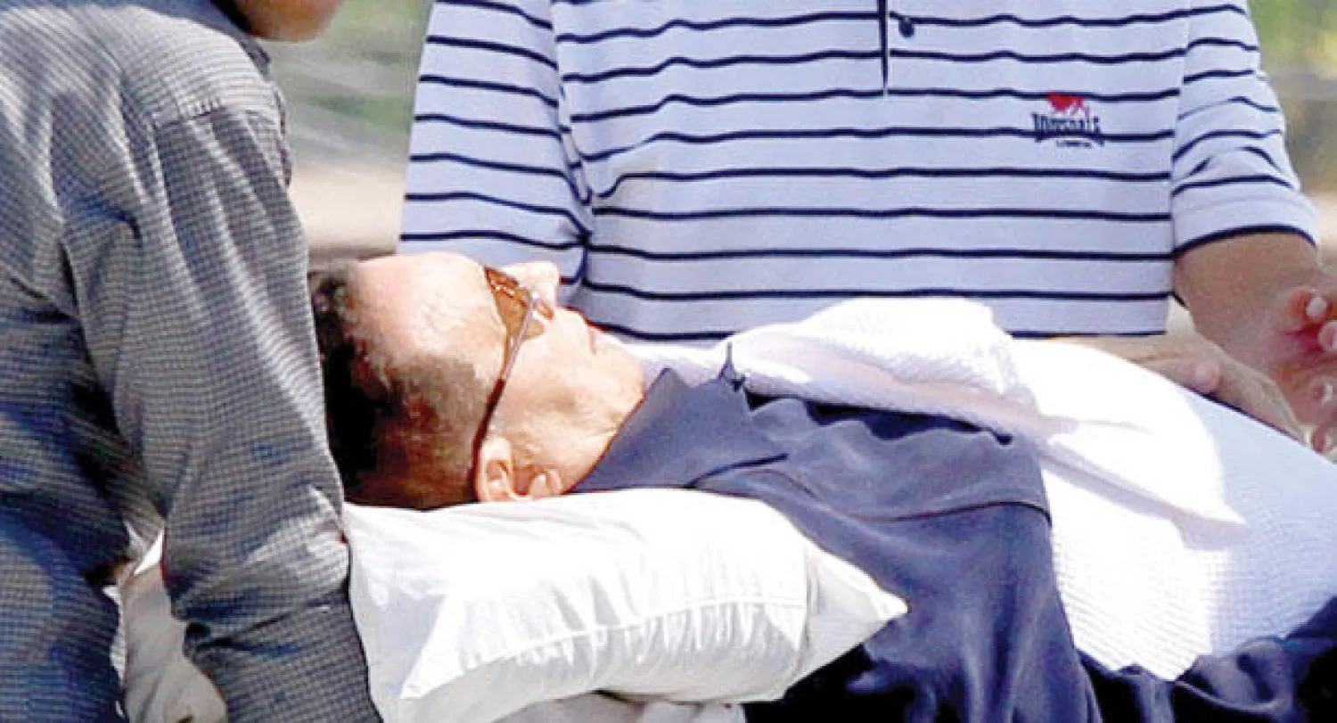 الرئيس المصري الأسبق حسني مبارك أثناء نقله من طائرة هليكوبتر إلى سيارة إسعاف لتقله إلى مكان محاكمته في القاهرة أمس.  (إ.ب.أ)