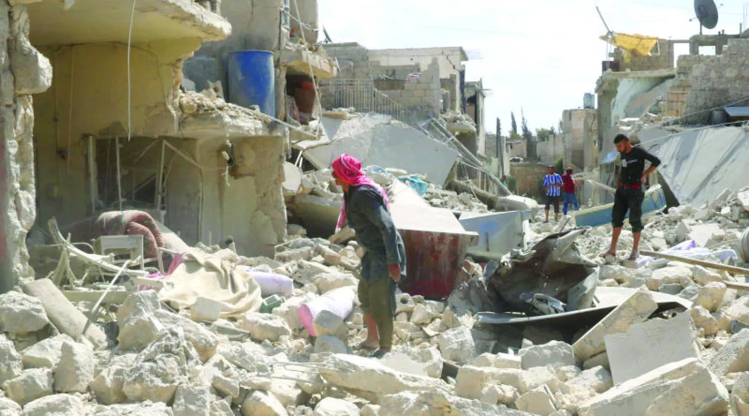 سوريون يعاينون الدمار الذي خلفه برميل متفجر ألقته القوات الحكومية على مدينة حلب أمس (أ.ف.ب)