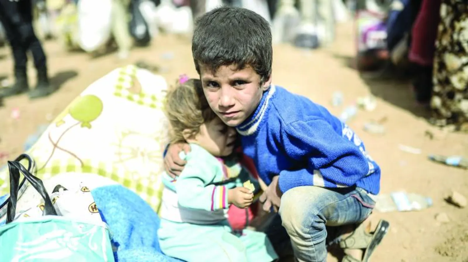 طفل سوري يحتضن شقيقته بعد فرارهما من كوباني ووصولهما الى الحدود التركية أمس (أ.ف.ب)