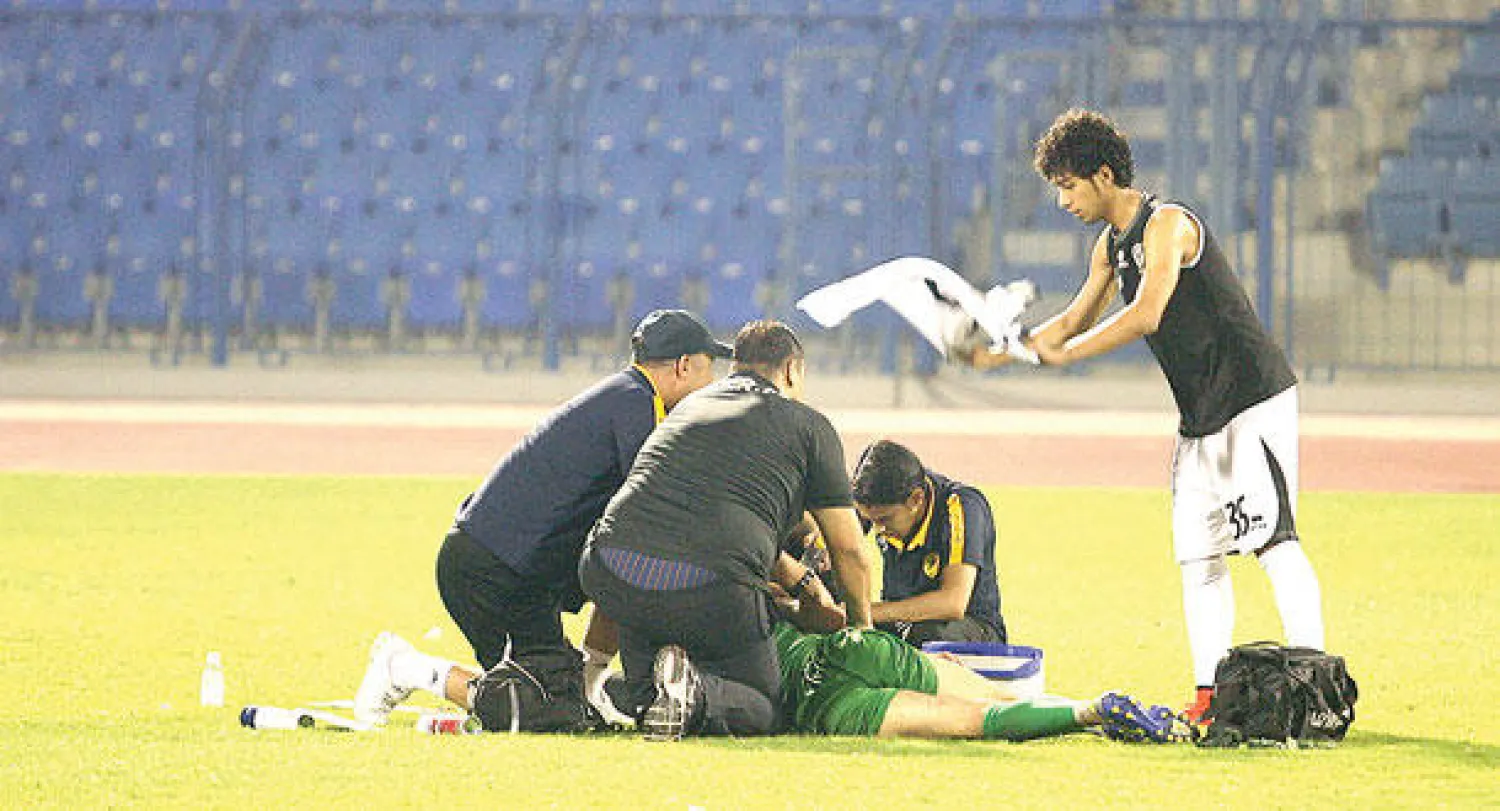 المسعفون يتحلقون حول الأردني عدنان بينما يشارك أحد لاعبي هجر في عملية إنقاذه (تصوير: عيسى الدبيسي)