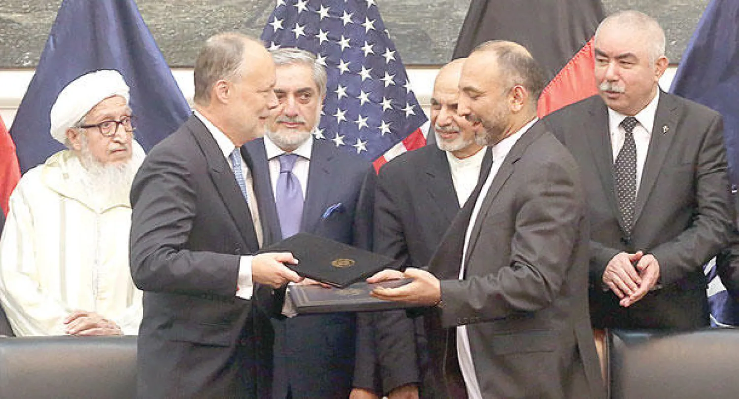 مستشار الأمن الأفغاني (يمين) والسفير الأميركي يتبادلان وثيقة الاتفاق الأمني بعد التوقيع في كابل أمس (أ.ب)